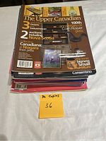 Stack of 30 magazines labeled as The Upper Canadian, showing 100th anniversary of Coin Flower glass on top issue cover.