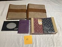 Photo showing six different photo albums of varying sizes and cover styles placed on a white surface.