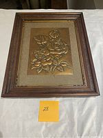 Full view of framed copper flower stamping with wooden and gold-trim frame