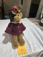 Full view of teddy bear sitting on small wooden chair with note 19 in front
