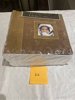 Front view of sealed pack of 3 brown photo albums with a child's photo in the front window of one album, wrapped in clear plastic.