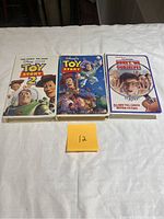 Front side of three VHS movies featuring Toy Story, Toy Story 2, and Honey We Shrunk The Kids with original sleeves lying on a white surface.