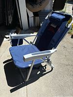 Single Tommy Bahama portable folding beach chair set up outdoors showing padded headrest and armrests.