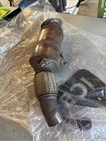 Full view of a BMW catalytic converter with flexible exhaust tubing.