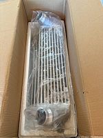 New intercooler in original box with protective plastic covering and attached blue silicone piping.