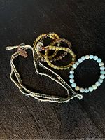 Photo showing five pieces of natural stone jewelry including bracelets and necklaces with various bead colors and metallic charms.
