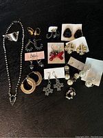 All assorted jewelry items displayed on black surface including necklaces, earrings, and brooches