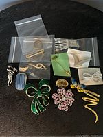 Photo showing assorted brooches of varying shapes, sizes, and colors arranged on a dark surface