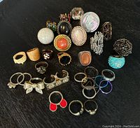 Photo showing assorted costume jewelry rings with various colors, materials, and designs.
