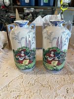 Front view of both vases showing colorful painted scenes of a woman playing a musical instrument