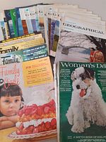 Overview photo showing a collection of magazines spread out, including multiple Canadian Geographical Journal issues, Family Circle 1956, and Woman's Day 1965.