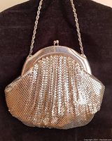 Full view of the vintage silver mesh purse showing its rounded shape, metal frame clasp, and chain handle.