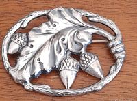 Front view of the sterling silver oak leaf and acorn brooch showing detailed design and textured edge.