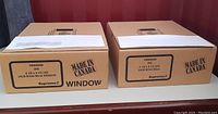 Two closed boxes labeled 'Made in Canada' containing white window envelopes and plain envelopes. Each box marked Supreme brand and size 4 1/8 x 9 1/2 inches with 24LB paper weight.