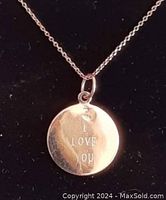 Close-up of 10K gold round charm pendant inscribed with 'I LOVE YOU' on thin chain.