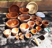Full view of assorted terracotta pots of multiple sizes, some painted and some plain, plus the enamelware plate, bulb planter, and twist tie included in the lot.