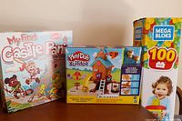 Photo showing My First Castle Panic board game, Play-Doh Builder Treehouse Kit, and Mega Bloks box together.