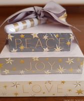 Stacked note pads showing sides with words 'PEACE', 'JOY', 'LOVE' and gold star pattern.