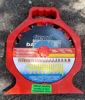 Red plastic carrying case holding a Freud 8 inch DADO blade with detailed instructions attached inside the case. Green label indicating shim set included.