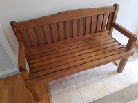 Front view of bench showing slatted seat and back with armrests