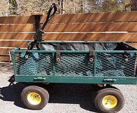 Side view of green steel mesh cart mounted on four 10" pneumatic tires with yellow hubs, showing fabric liner and drop-down sides
