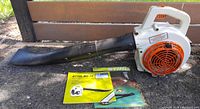 Stihl BG 72 blower with attached black nozzle tube and two printed owner manuals displayed on the ground.