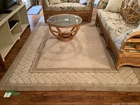 Overview of rug under rattan seating and glass-top coffee table