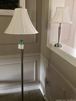 Both floor lamp and table lamp shown side by side, with white lamp shades and brushed metal finishes