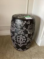 Full side view of barrel-shaped black and white ceramic stool with floral pattern