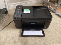 Front side view of Canon MX492 printer showing paper tray extended with paper loaded and control panel keys.