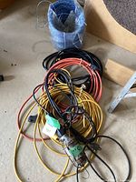 Three extension cords coiled: orange, yellow, black, with portable work light partially visible.