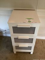White IKEA cabinet with three semi-transparent ribbed drawers, white handles visible, photographed from above and front.