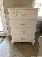 Front view of white IKEA dresser showing 4 drawers with metal handles and a label on top drawer.