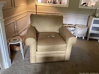 Front view of the gold La-Z-Boy recliner chair showing the cushioned backrest and rolled armrests in a family room environment.