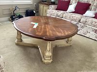 Photo of round coffee table showing wooden top and beige base in living room setting