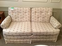 Full front view of the loveseat showing the two seat cushions, floral upholstery, and rolled arms.