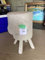 Photo of the full wood stool showing its three angled legs and cylindrical trunk body painted white.
