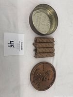 Photo showing two metal tins with embossed Lincoln penny lids and five paper rolls of pennies, with auction lot card.