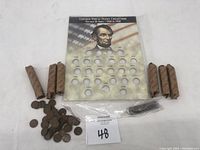 Full lot showing the collection holder, multiple wrapped rolls of pennies, and loose pennies scattered on the surface.