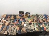 Wide layout of over 50 vintage magazine cutouts of famous actresses arranged on a black surface showcasing diversity in portraits and styles mostly in color with some black and white.