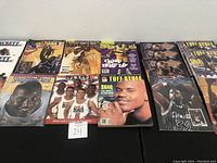 Photo showing an assortment of basketball magazines featuring Shaquille O'Neal on the covers with various basketball images and team uniforms.