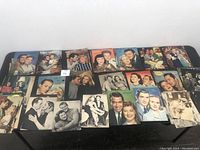 Table with about twenty vintage magazine cutouts showing famous couples in romantic poses, some in color others in monochrome.