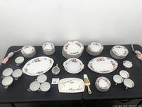 Full view of the dinnerware set including various plates, cups, saucers, platters, sugar bowl, and butter dish with spreader all with pink floral designs on white porcelain.