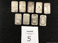 Set of 11 silver-tone engraved metallic pieces showing details of different celebratory engravings and some tarnishing due to use.