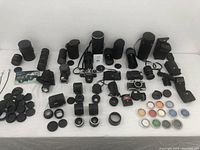 Full overview of all camera lenses, bodies, flash units, lens caps, and accessories arranged on a white surface