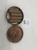Tin containing four rolls of pennies and a large embossed penny design on lid