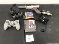 Photo showing Nintendo Zapper, NES controller, third-party controller, NES power adapter, and three NES game cartridges on a table.