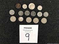 Top view of assorted U.S. coins including pennies, dimes, nickels arranged on black surface.