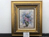 Frontal image of the painting in its ornate gold and bronze frame with floral and leaf patterns, showing the full artwork and frame.