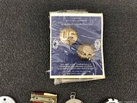 Photo shows a blue card with two 18 karat gold plated Western Military Insignia pins in original packaging.